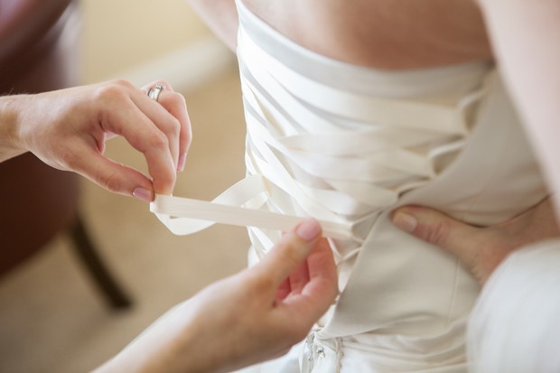 bride having corset wedding dress tied