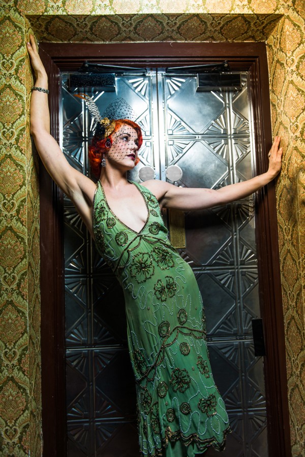 Model with red hair, green and gold flapper dress, vintage jewelery, birdcage